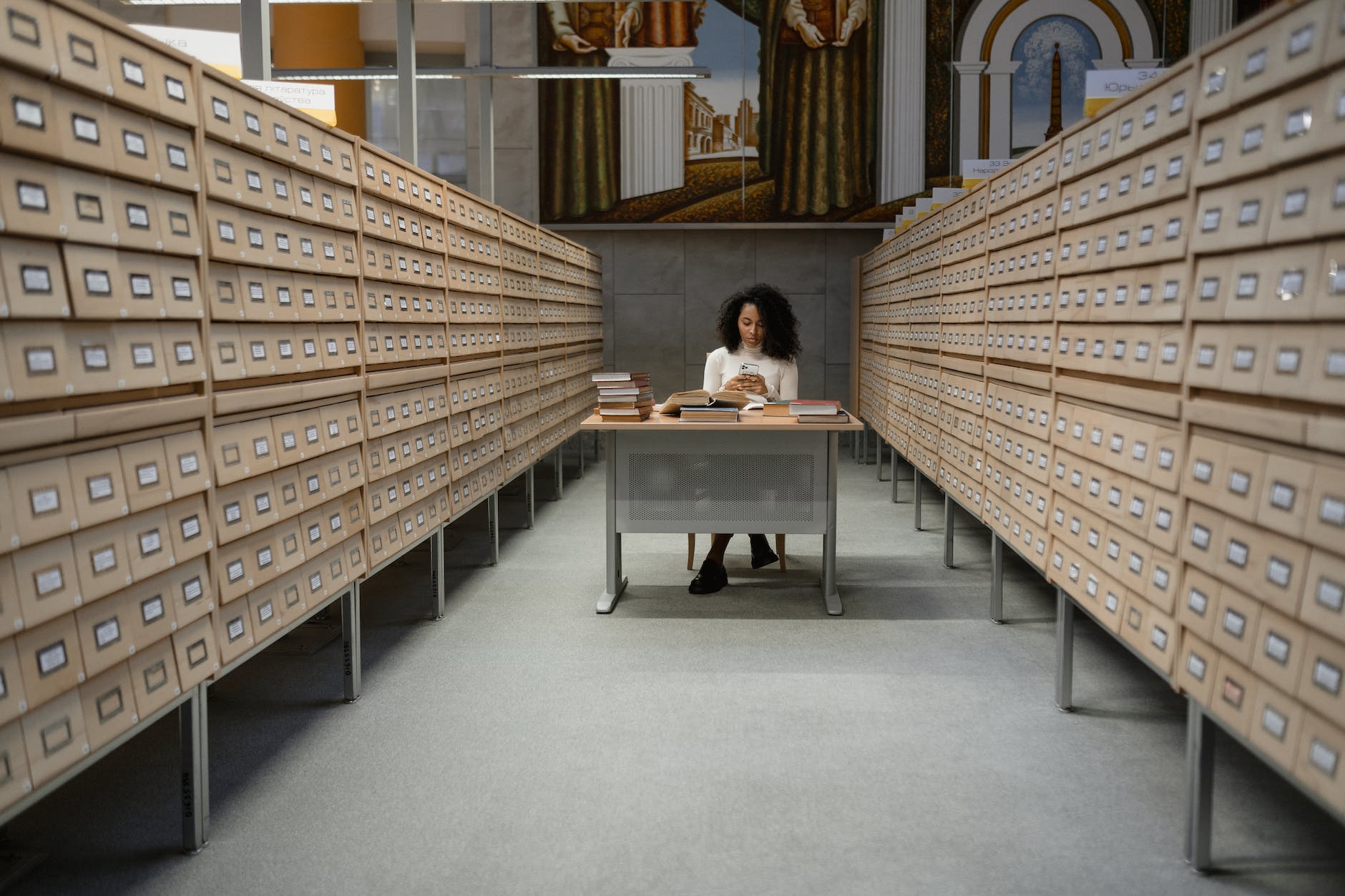 a girl sitting in front of a table between database wooden drawer