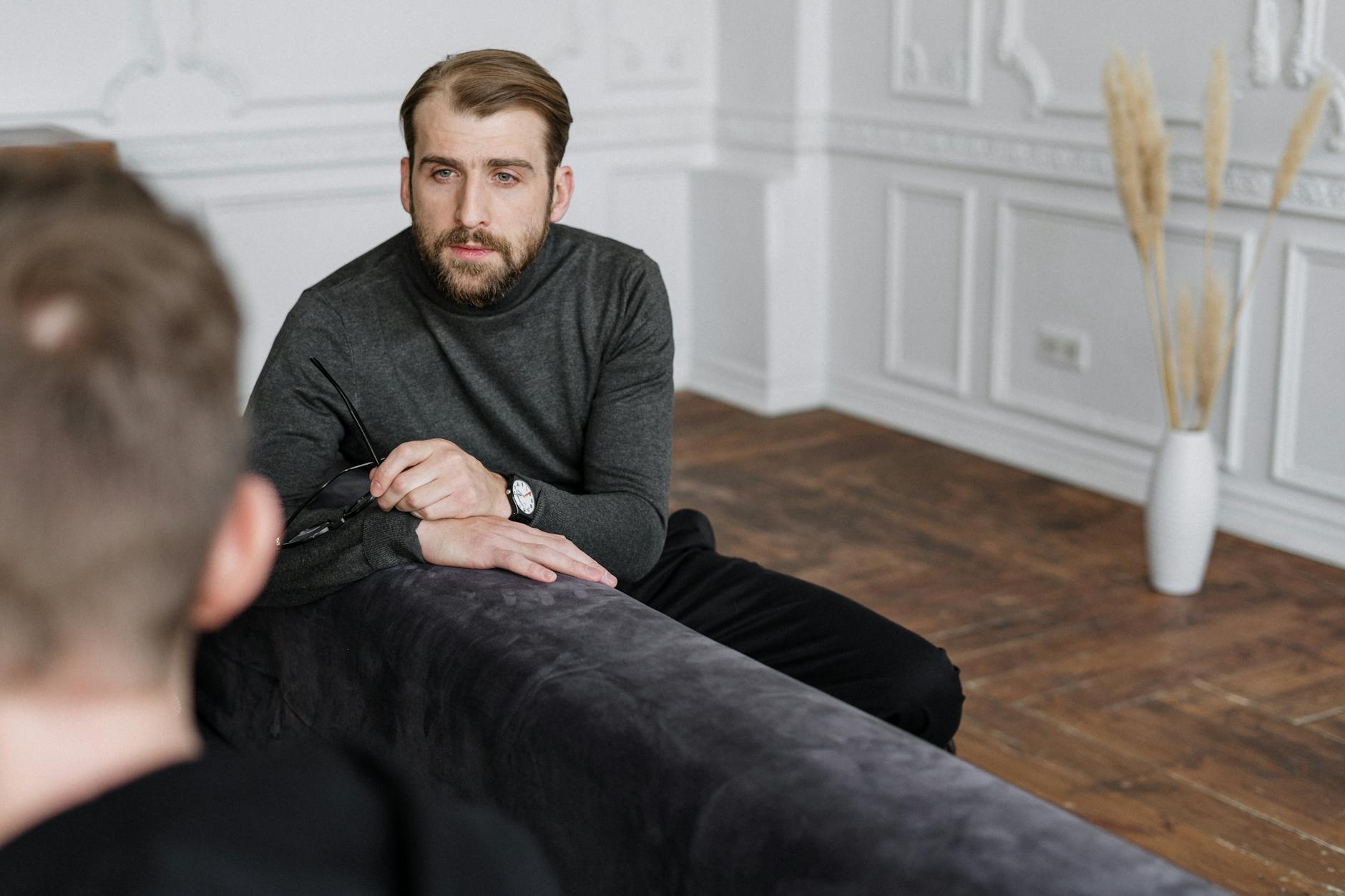 man in gray sweater sitting on black couch